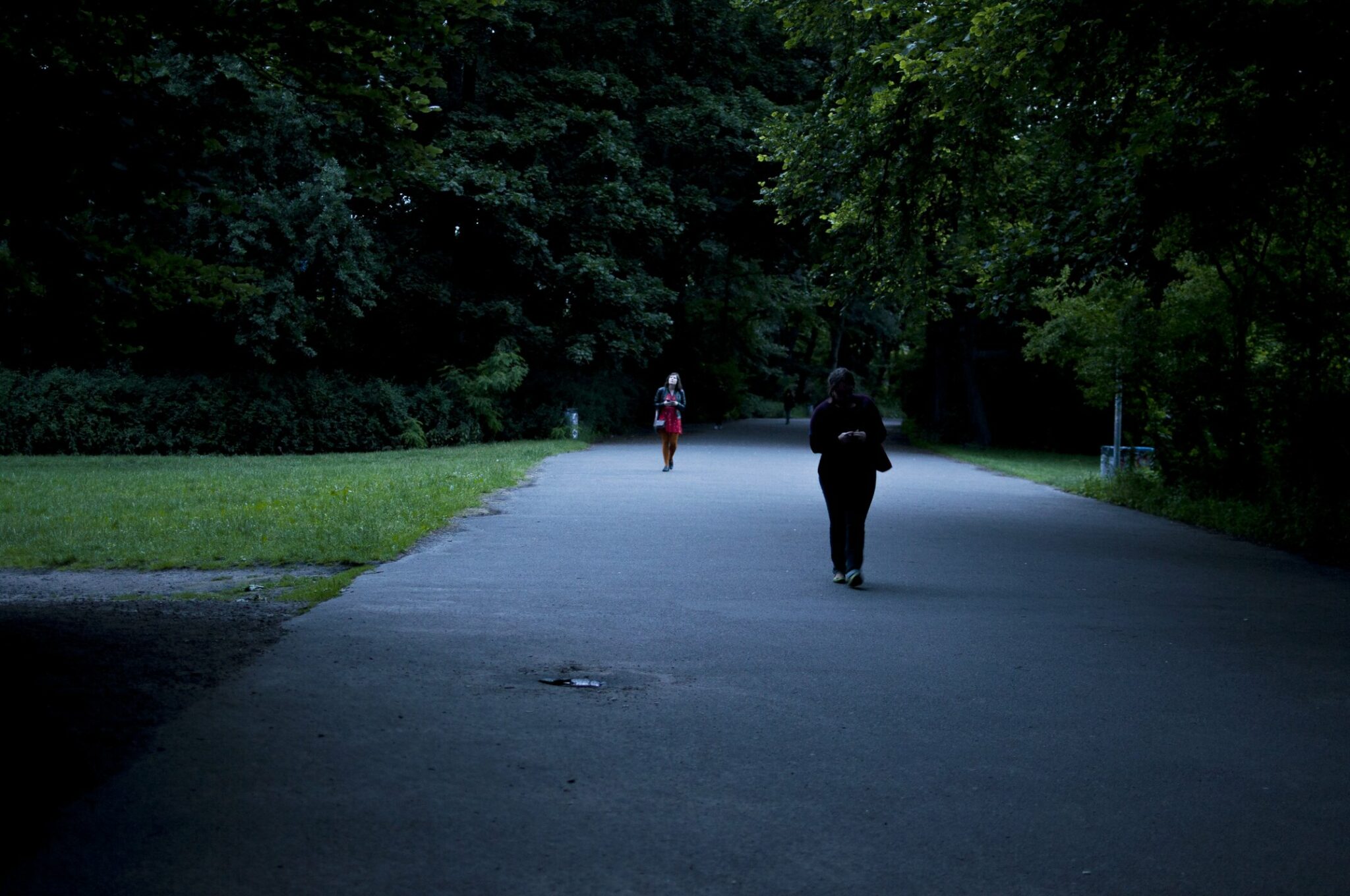 Zwei Personen laufen durch einen Park in der Dämmerung.